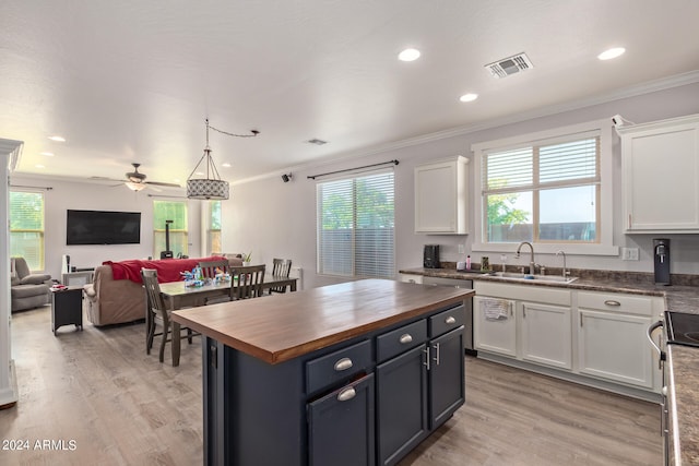 kitchen with butcher block counters, white cabinetry, sink, and a wealth of natural light