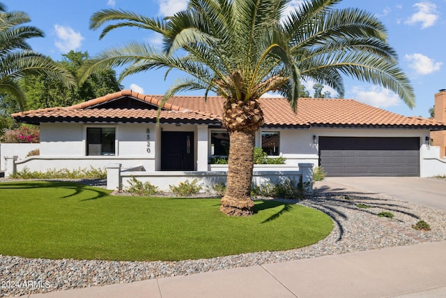 mediterranean / spanish house featuring a garage and a front yard