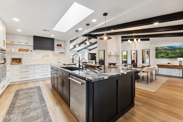 kitchen with light hardwood / wood-style flooring, hanging light fixtures, a kitchen island with sink, and sink