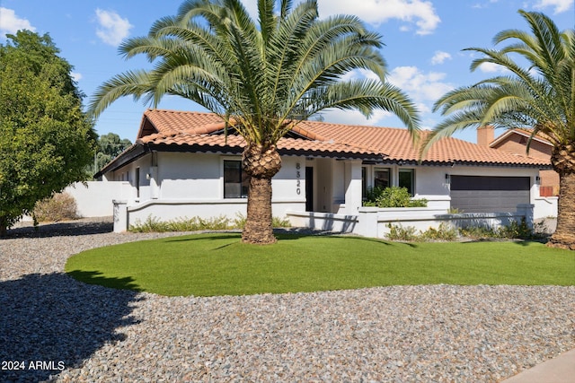 mediterranean / spanish house featuring a garage and a front lawn