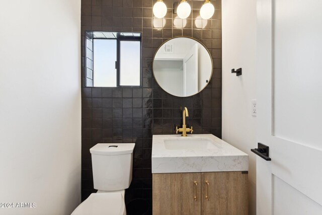 bathroom with vanity, tile walls, and toilet