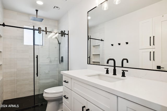 bathroom with a shower with door, vanity, and toilet