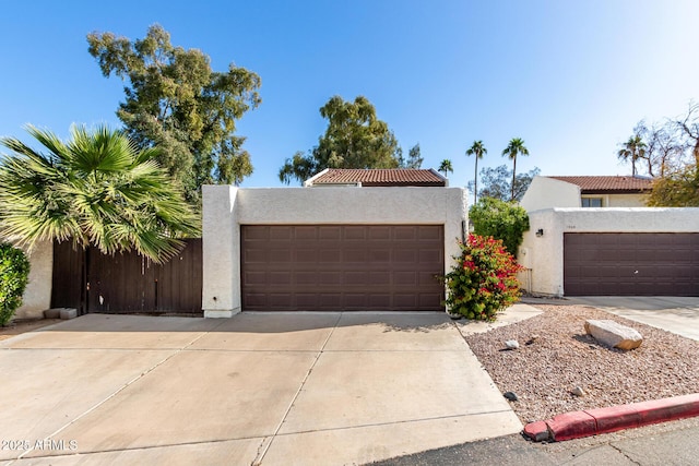 view of front facade with stucco siding, a tile roof, and a garage