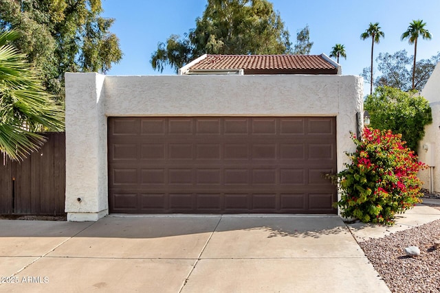 garage featuring concrete driveway and fence