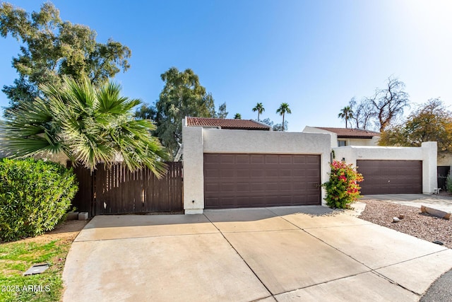 view of front of home featuring an attached garage, fence, driveway, and stucco siding