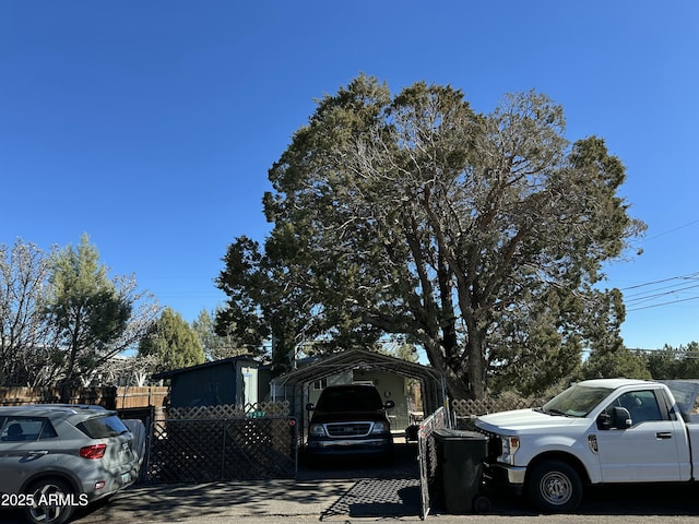 view of vehicle parking featuring fence and a detached carport