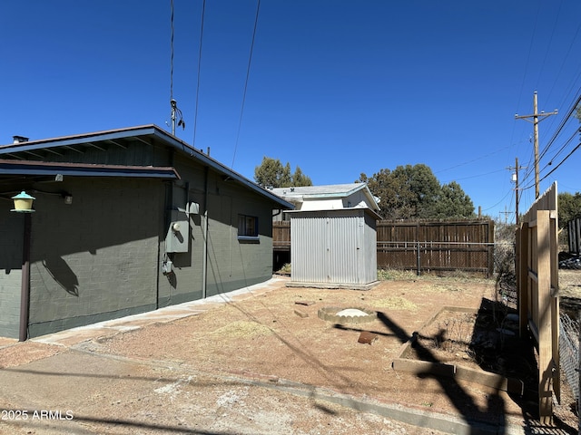 view of side of property featuring brick siding, a storage shed, fence, and an outdoor structure