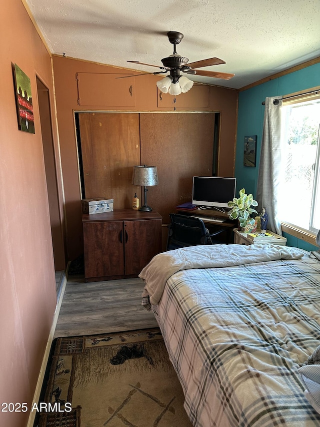 bedroom with dark wood-type flooring, crown molding, a textured ceiling, and a ceiling fan