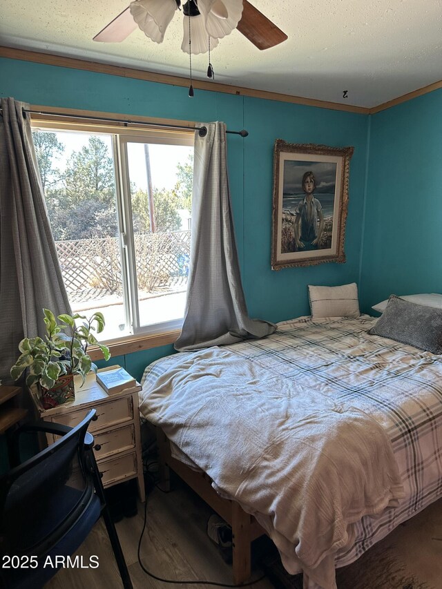 bedroom with a textured ceiling, multiple windows, a ceiling fan, and crown molding