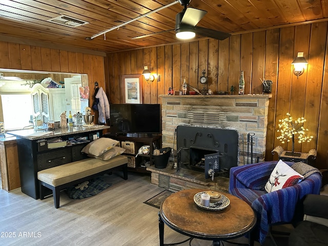 living room featuring wooden walls, visible vents, wooden ceiling, ceiling fan, and light wood-type flooring