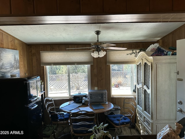 interior space with a textured ceiling, a wealth of natural light, wood walls, and freestanding refrigerator