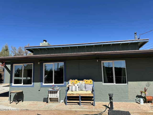 back of property featuring a chimney, concrete block siding, and a patio