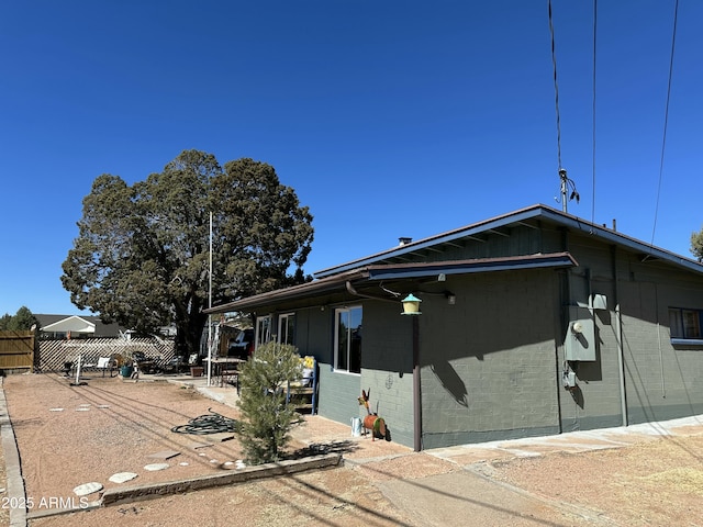 view of front of house with a patio area, fence, and brick siding