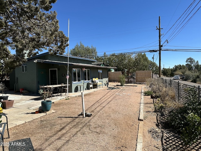 rear view of property featuring concrete block siding, fence, and a patio