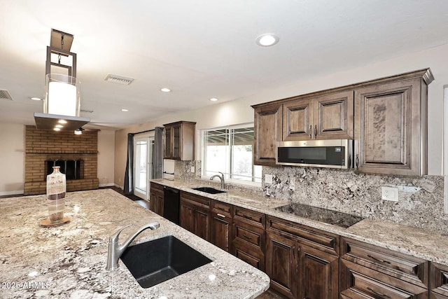 kitchen with light stone counters, sink, tasteful backsplash, and black appliances