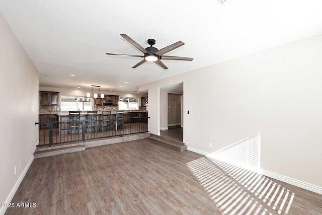 unfurnished living room featuring dark wood-type flooring and ceiling fan