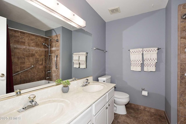 full bathroom with tile patterned flooring, tiled shower / bath, vanity, and toilet