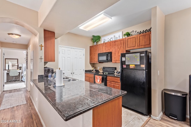 kitchen with sink, black appliances, kitchen peninsula, and light hardwood / wood-style floors