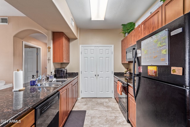 kitchen with black appliances, sink, and dark stone counters