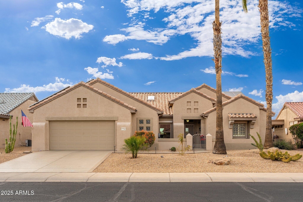 view of front of home featuring stucco siding, an attached garage, a gate, fence, and a tiled roof