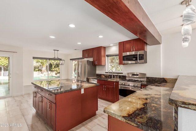 kitchen with a kitchen island, sink, dark stone counters, hanging light fixtures, and stainless steel appliances