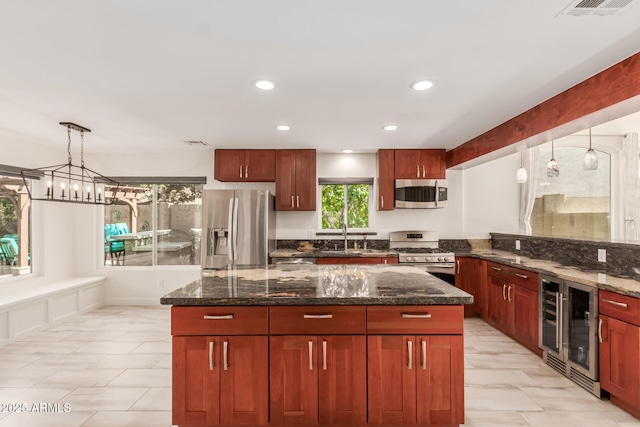 kitchen with sink, appliances with stainless steel finishes, decorative light fixtures, beverage cooler, and dark stone counters