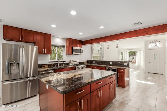 kitchen with sink, decorative light fixtures, dark stone counters, a kitchen island, and stainless steel appliances