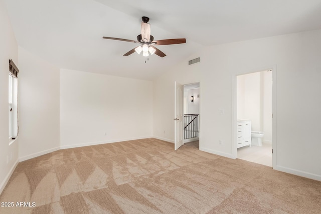 unfurnished bedroom featuring light carpet, ensuite bath, and lofted ceiling