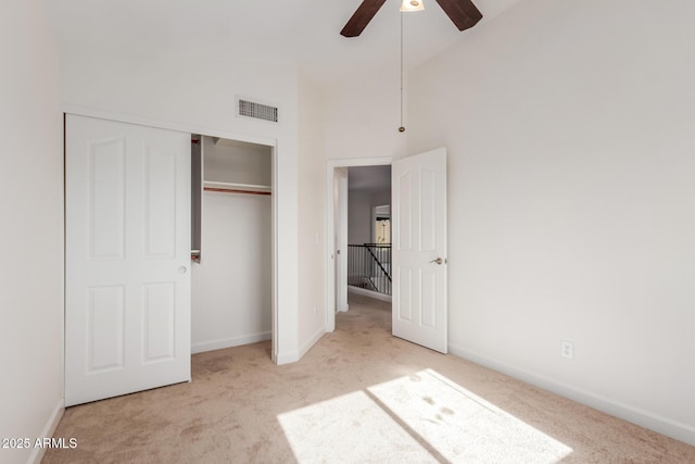 unfurnished bedroom featuring ceiling fan, light colored carpet, high vaulted ceiling, and a closet