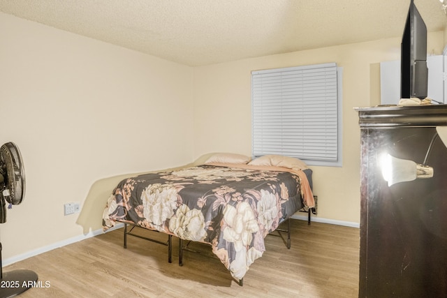 bedroom with a textured ceiling and light wood-type flooring