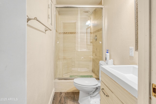 bathroom featuring hardwood / wood-style flooring, vanity, an enclosed shower, and toilet