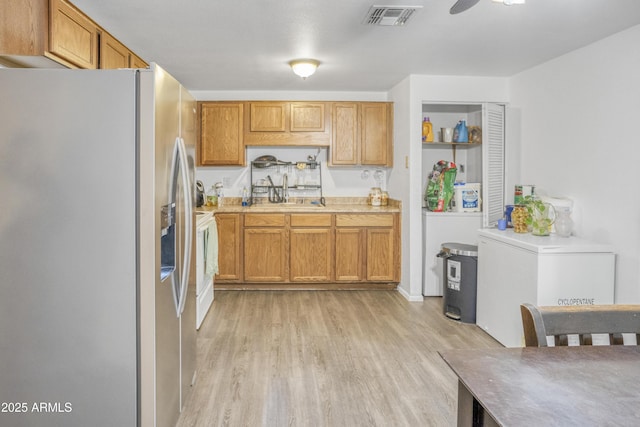 kitchen featuring refrigerator, sink, ceiling fan, light hardwood / wood-style floors, and stainless steel refrigerator with ice dispenser