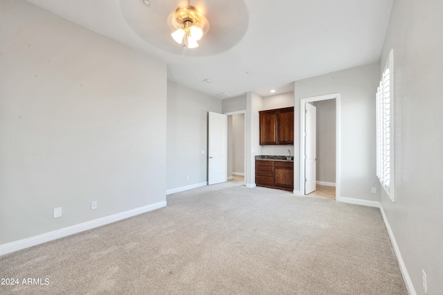 unfurnished living room featuring light carpet and ceiling fan