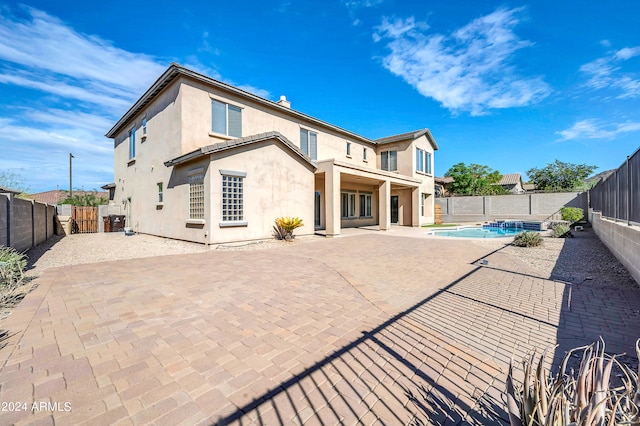 rear view of property with a fenced in pool and a patio area