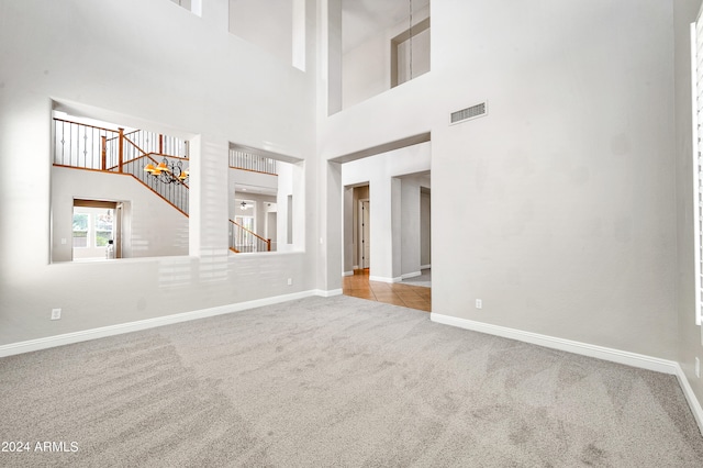 spare room featuring a towering ceiling and light carpet