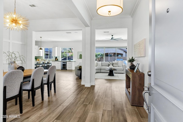 3038 E Longhorn Dr, Gilbert, AZ 85297 - dining area featuring wine cooler, wood finished floors, a chandelier, ceiling fan, and ornamental molding
