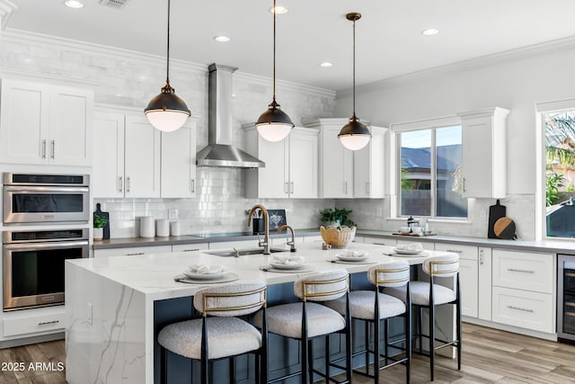 3038 E Longhorn Dr, Gilbert, AZ 85297 - kitchen featuring wall chimney exhaust hood, a sink, double oven, tasteful backsplash, and a center island with sink