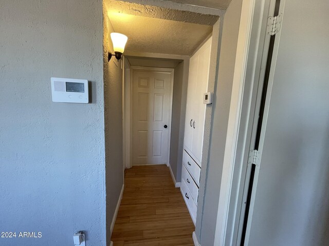 corridor with hardwood / wood-style floors and a textured ceiling