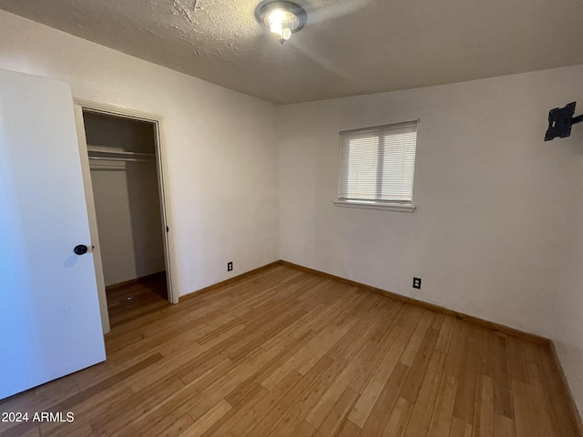 unfurnished bedroom with a closet, a textured ceiling, and light wood-type flooring