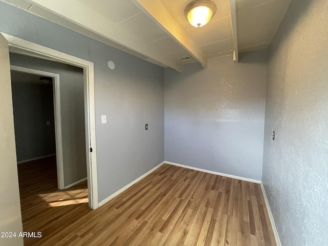 spare room with beam ceiling and hardwood / wood-style flooring