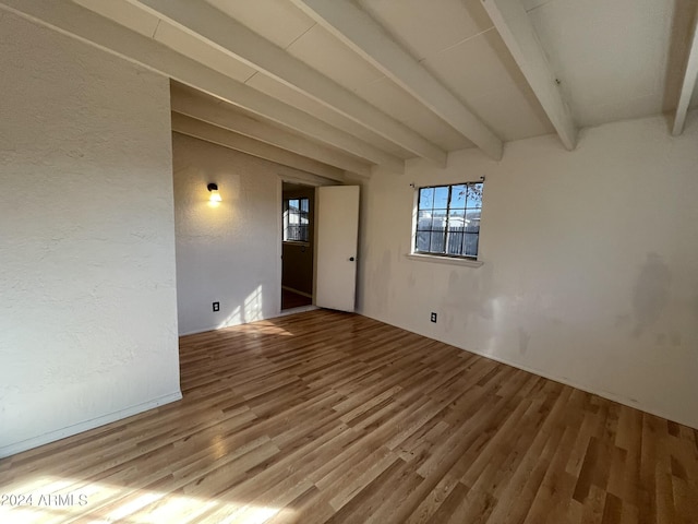 empty room with beamed ceiling and hardwood / wood-style flooring