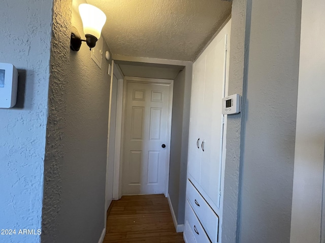 hallway with hardwood / wood-style flooring and a textured ceiling