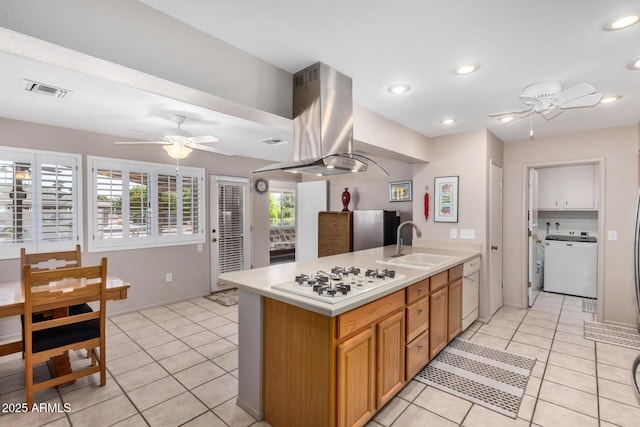 kitchen with white appliances, washer / clothes dryer, a sink, ceiling fan, and island range hood