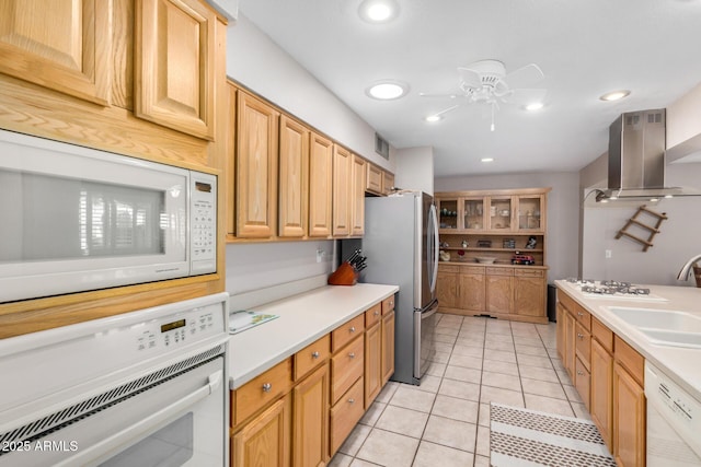 kitchen featuring white appliances, light countertops, range hood, and a sink