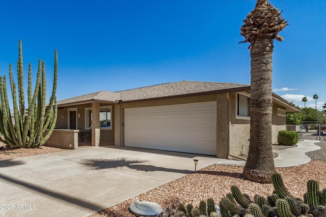 view of front of home with stucco siding, driveway, fence, roof with shingles, and a garage