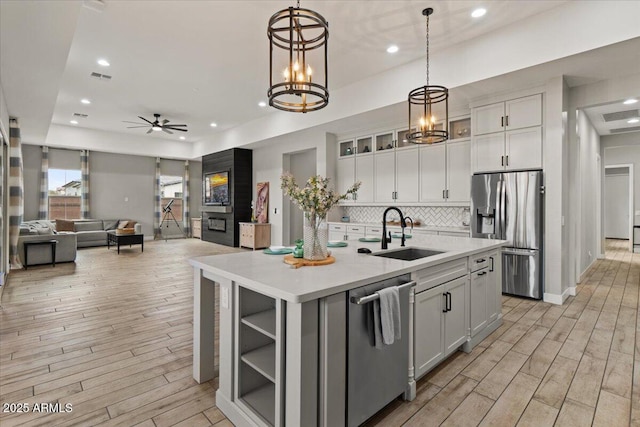 kitchen featuring stainless steel appliances, an island with sink, sink, and white cabinets