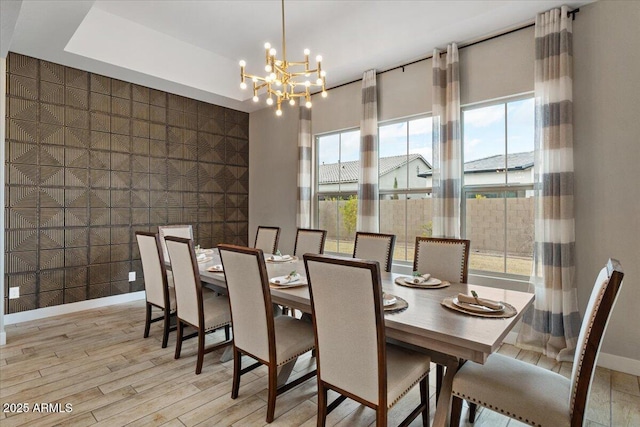 dining room featuring a healthy amount of sunlight, an inviting chandelier, and light wood-type flooring