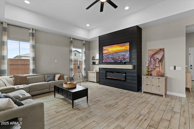 living room featuring ceiling fan and a large fireplace