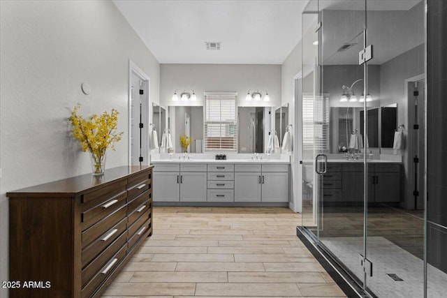 bathroom featuring a shower with door and vanity