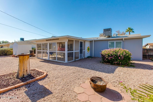 rear view of property featuring a sunroom, central AC unit, and a storage shed